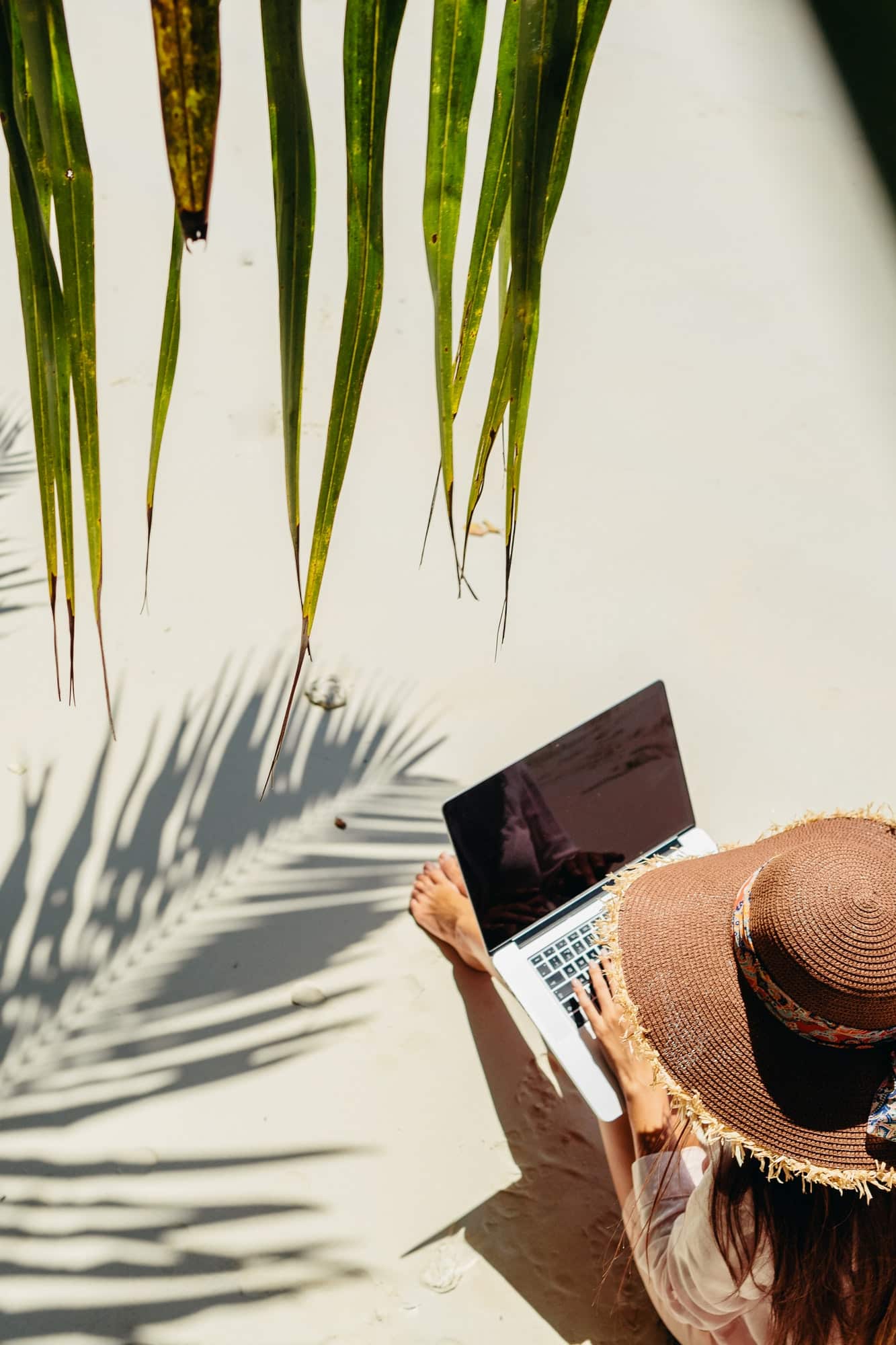 woman working remotely on laptop on beach in tropics